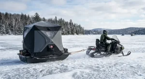 Bilingual English and French ice safety guide sign on a frozen lake with ice fishing shelters in the background.