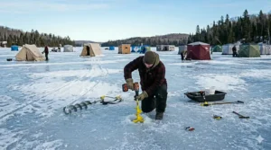 An illustration of a cordless drill with an adapter used to quickly drive ice shelter anchors into a frozen surface.