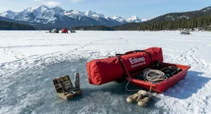 A rugged red sled carrying a collapsed portable ice shanty across deep snow for easy transport on frozen Canadian lakes.