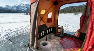 The detailed interior of a portable ice shanty with fishing holes, gear storage, and a heater for cold-weather comfort.