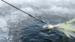 A close-up of a heavy-duty steel wire leader connected to a bright, feathered pike jig.