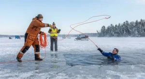 An ice fisher demonstrating how to throw an ice fishing rescue rope to a partner simulating a man-overboard emergency on frozen water.