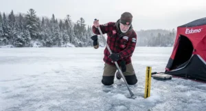 Using an ice spud bar to test safe ice thickness before winter ice fishing in Canada